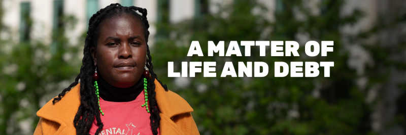 Women standig in front of trees wearng orange and red clothes with 'a matter of life and debt' written on top